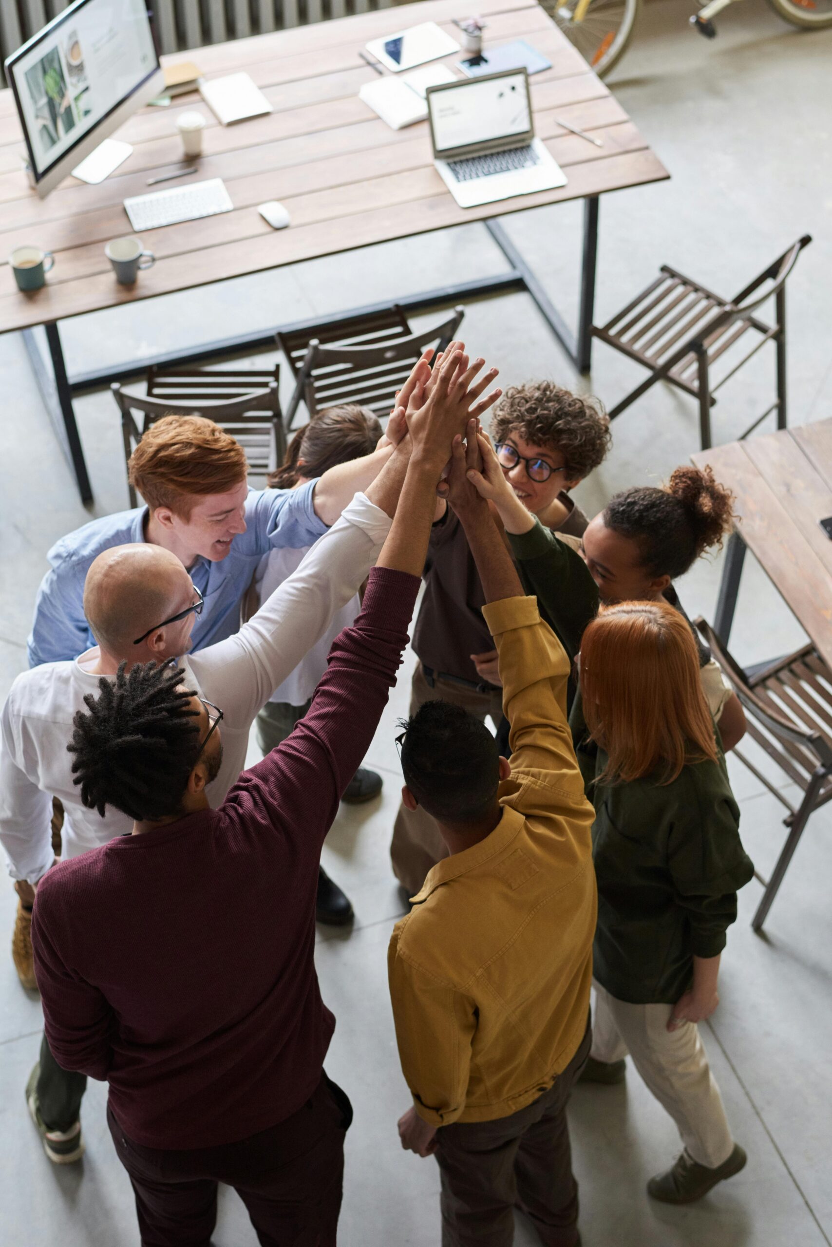 A diverse group of professionals high-fiving in a modern office, showcasing teamwork and collaboration.