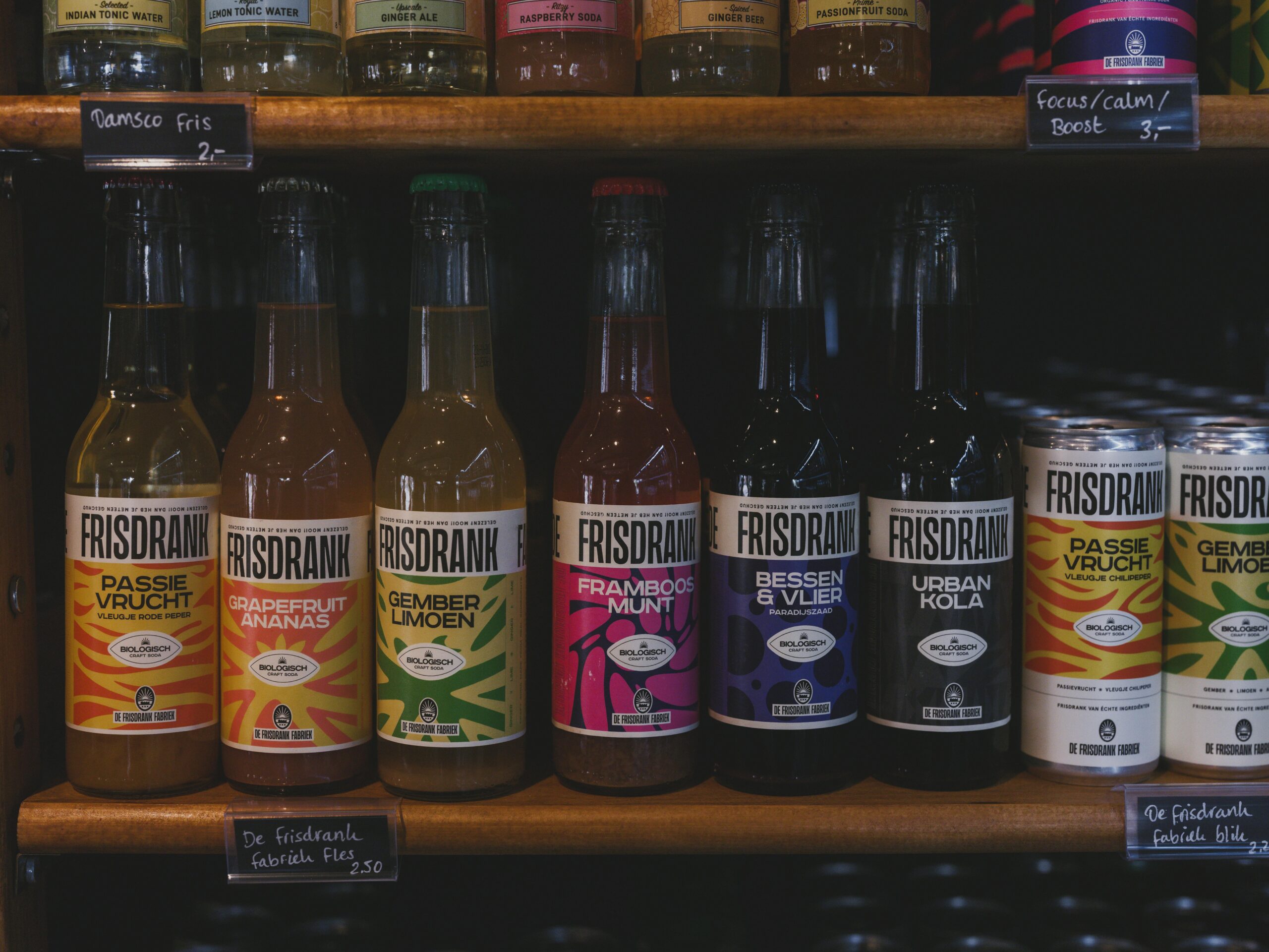 Vibrant collection of Frisdrank bottles and cans displayed on a supermarket shelf in Almere.