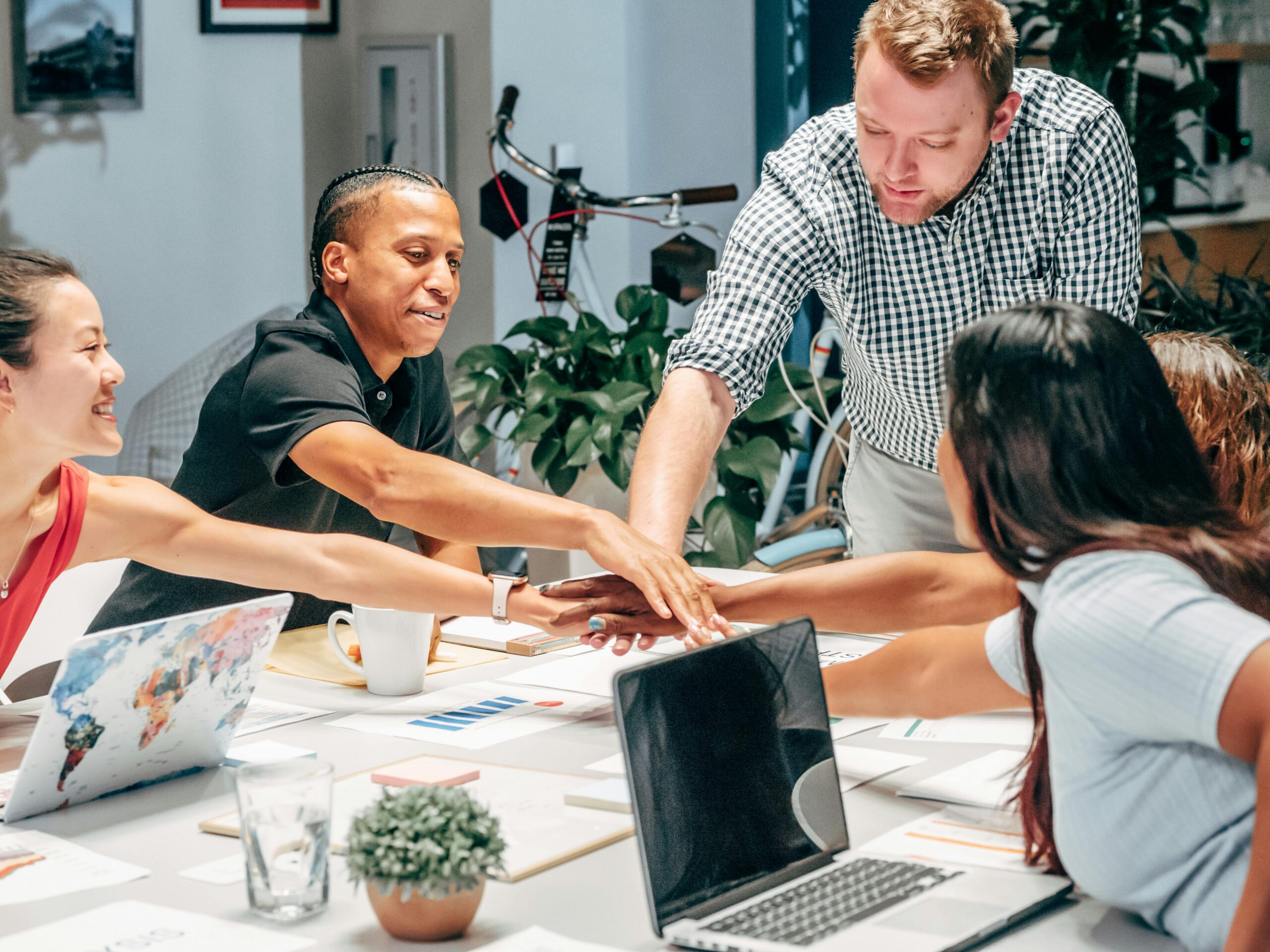A diverse group of colleagues in a meeting, stacking hands for teamwork.
